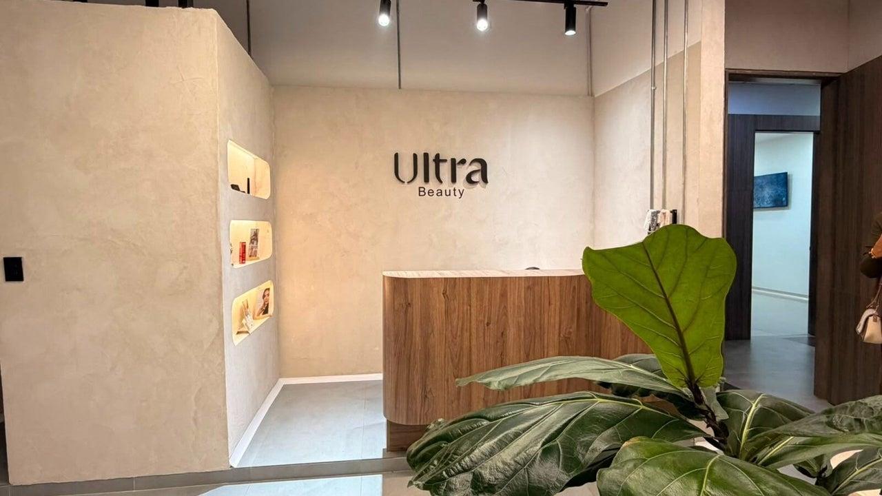 Recepción de Ultra Beauty con el logo en la pared y una planta
