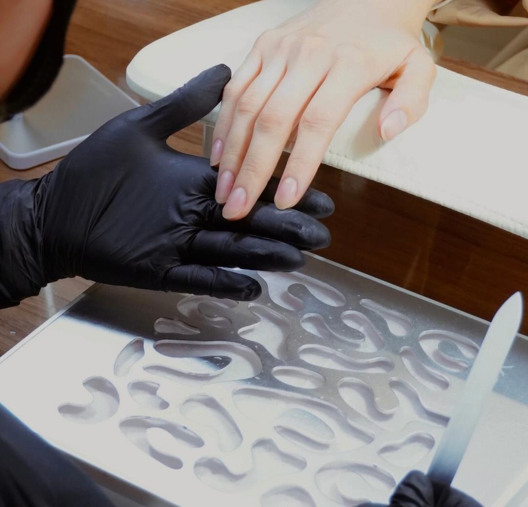 Mano sobre la bandeja de trabajo durante la Medical Mani